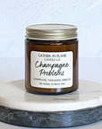 A jar candle with a label reading 'Champagne Problems' and topped with multi-colored eco-glitter, sitting on a marble surface.