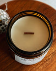 Candle in an open jar on a wooden surface with a disco ball in the background