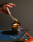 Hand lighting a candle on a stack of books with a dark background