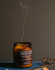 Candle labeled 'Champagne Problems' with a pair of wick trimmers on a dark surface