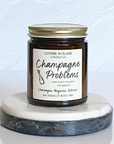 A jar candle with a label reading 'Champagne Problems' and topped with multi-colored eco-glitter, sitting on a marble surface.