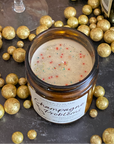 A jar candle with a label reading 'Champagne Problems' surrounded by gold metallic balls and showing eco-glitter on top