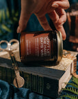 Hand holding a candle labeled 'Don't Let the Days Win' over an open book with decorative elements.