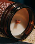 Candle in an amber jar with a decorative label on a textured surface