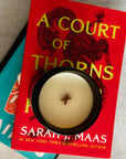 Book titled 'A Court of Thorns' by Sarah J. Maas with a candle on top