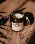Candle in a glass jar labeled 'Relax & Release' on a wooden surface with shadows.