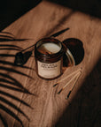 Candle labeled 'Relax Release' on a wooden surface with leaf shadows