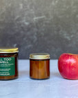 Two candles of different sizes and an apple on a textured surface with a gray background
