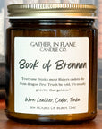 Close up of a jar candle labeled 'Book of Brennan' on a wooden stand, with a background of books.