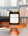 A jar candle labeled 'Book of Brennan' on a wooden stand, with a background of books.
