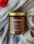 Jar of 'Cardigan' candle on a textured fabric background and raspberries