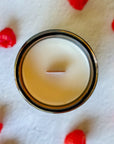 Cardigan candle in a amber glass jar on a white surface with raspberries