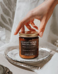 Candle labeled 'Champagne Problems' held by a hand on a decorative plate.