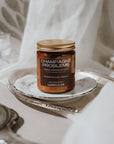 Jar of candle labeled 'Champagne Problems' on a silver tray with a soft background