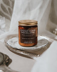 Jar of candle labeled 'Champagne Problems' on a decorative tray with a soft background