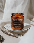 Candle jar labeled 'Champagne Problems' on a silver tray with a white cloth background