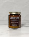 Candle jar labeled 'Champagne Problems' on a white background