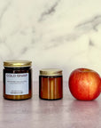 Two candles of different sizes labeled 'Cold Snap' and an apple on a marble surface