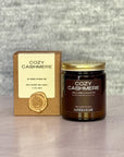 Cozy Cashmere candle with packaging on a textured surface
