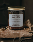 Candle jar labeled 'Fated Mates' on a dark background with dried flowers and scissors.