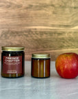 Two candles of different sizes and an apple on a light surface with a wooden background