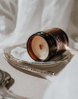 Candle jar in a decorative holder on a white surface