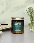 Candle jar labeled 'Glass Garden' on a table with a blurred background