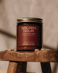 Candle jar labeled 'Golden Hour' on a wooden stand with a blurred background
