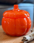 Orange pumpkin-shaped container on a wooden surface with a blurred background