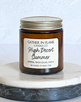 A jar candle with a label reading 'High Desert Summer', placed on a marble surface.