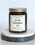 A jar candle with a white label that reads 'In My Romantasy Era', placed on a marble surface.