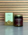 Candle labeled 'Last of the Harvest' with packaging on a striped background