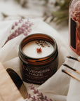 Lavender-scented candle in a jar with matches and a book on a soft surface
