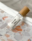 A clear glass roller bottle of 'Lavender Haze' perfume oil with a bamboo cap, placed on a terrazzo surface.