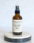 A brown amber spray bottle labeled 'Lavender Haze' by Gather In Flame Candle Co. on a white marble surface.