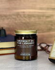 Candle jar labeled 'Midnight in the Library' with a clock and books in the background