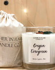 Clear glass 12oz Oregon Evergreen candle on a shelf next to a muslin bag labeled Gather in Flame Candle Co