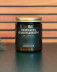 Jar of 'Oregon Evergreen' candle with a gold lid on a wooden surface