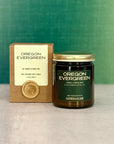 'Oregon Evergreen' candle with packaging and wax seal on a grey surface with green background