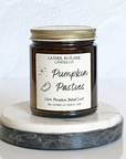 A jar candle with a label reading 'Pumpkin Pasties' on a marble-like surface.