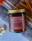 Flatlay photo of 'Spiced Plotlines' candle with cinnamon sticks, mini marshmallows and an small pumpkin in the background