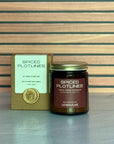 Candle and packaging with 'Spiced Plotlines' branding on a striped background