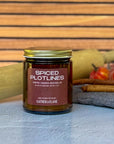 Jar of 'Spiced Plotlines' candle with cinnamon sticks, a rolling pin and pumpkins in the background