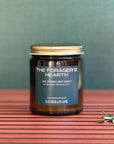 Candle labeled The Forager's Hearth on wooden background