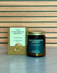 Candle labeled The Forager's Hearth with packaging on wooden background