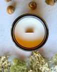 Overhead view of candle with wood wick surrounded by acorns and moss