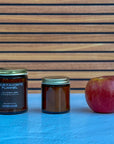 Two candles of different sizes and an apple on a blue surface with a wooden background