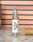A perfume oil roller with a clear glass body and a bamboo cap sitting beside it, labeled 'Your Favorite Flannel' on a terrazzo surface with wood background.