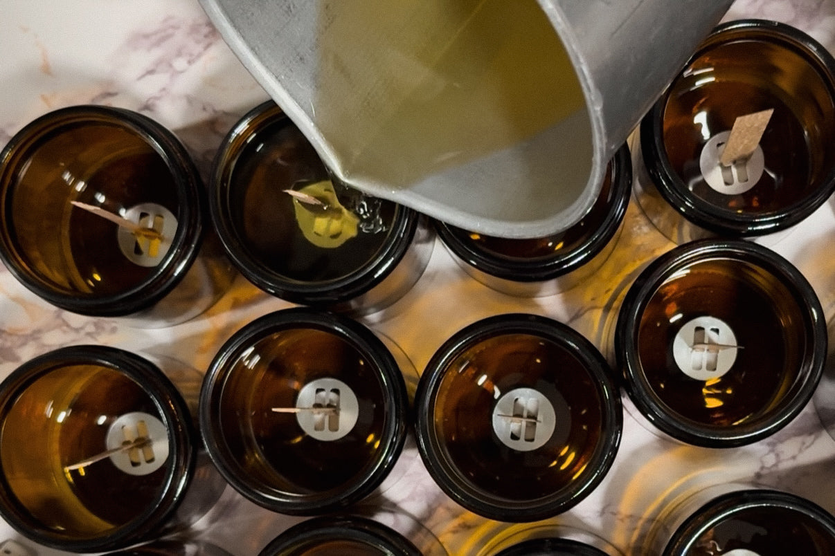 Pouring creamy coconut wax into amber glass jars for crackling wood wick candles by Gather in Flame.