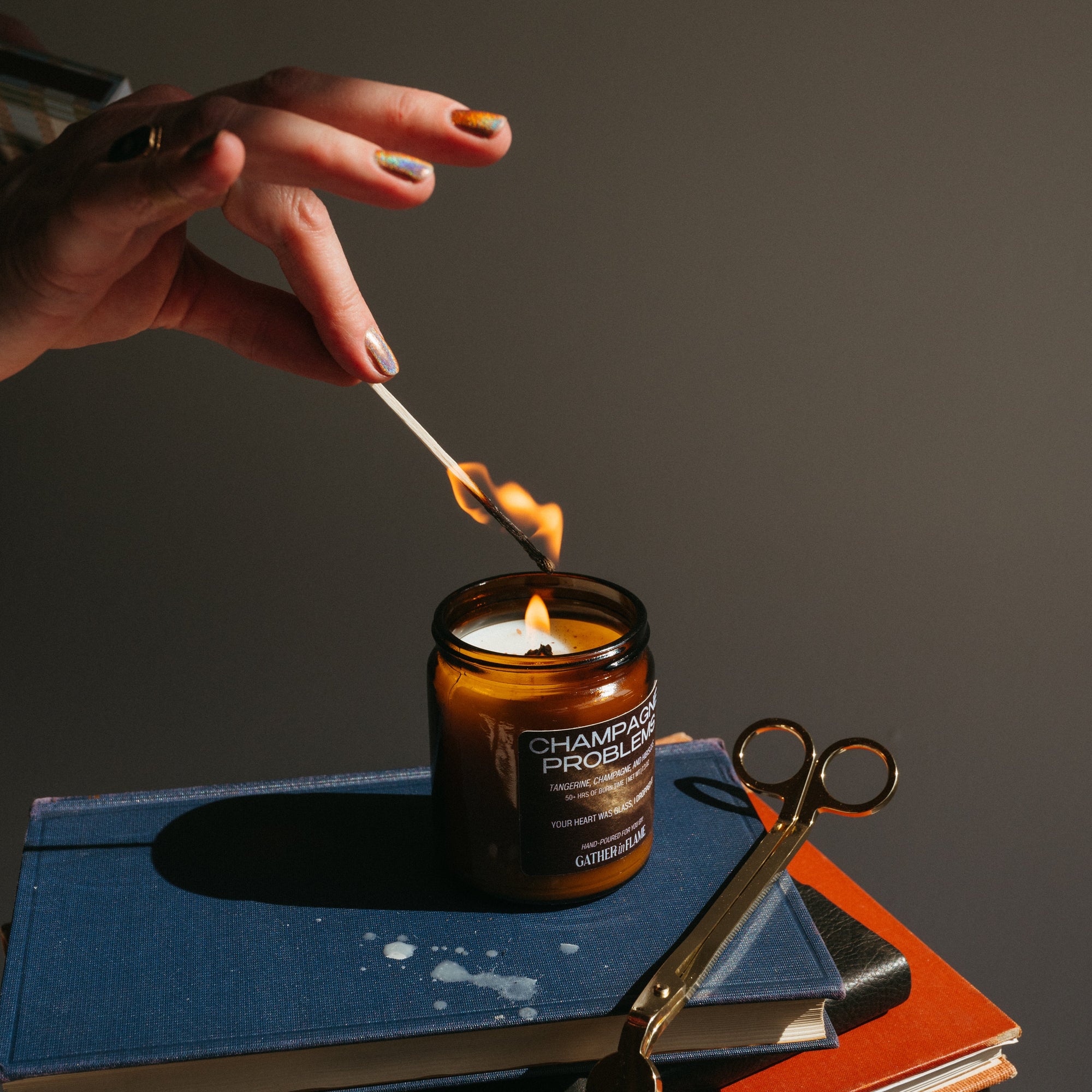 Hand lighting a candle on a stack of books with a dark background